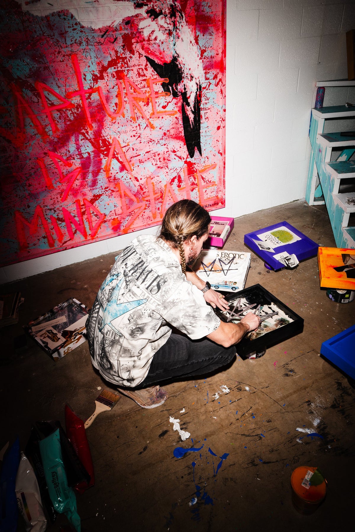 not.travis working in his studio beneath a large red painting